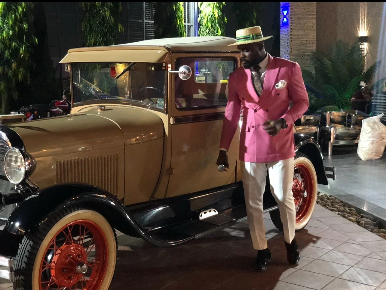 A guest arriving beside a vintage gold car at De Icon