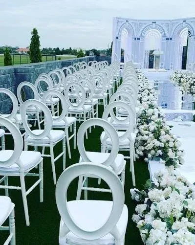 White flowers and rows of circular chairs in an outdoor ceremony setting