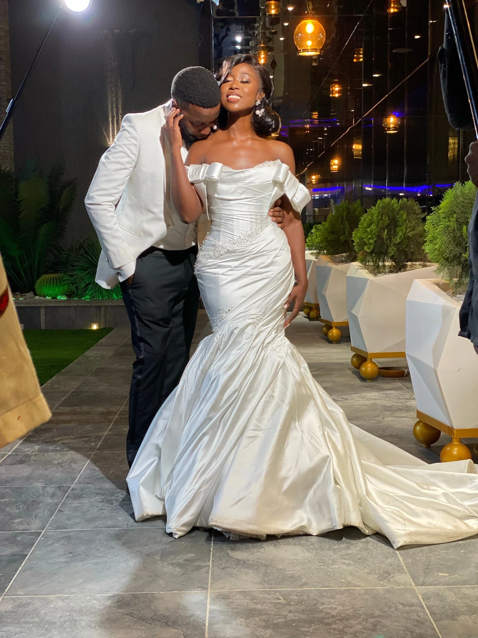 A bride and groom at De Icon, with warm pendant lighting behind them
