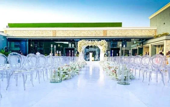 An outdoor ceremony setting with white seating and floral decorations