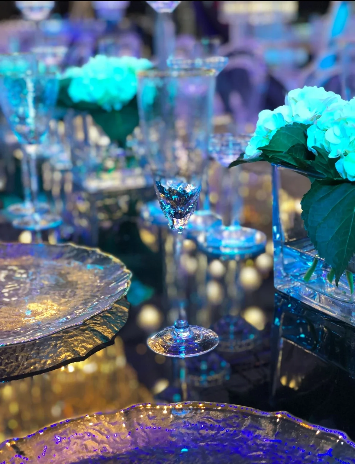 Gold place settings and glassware under blue event lighting